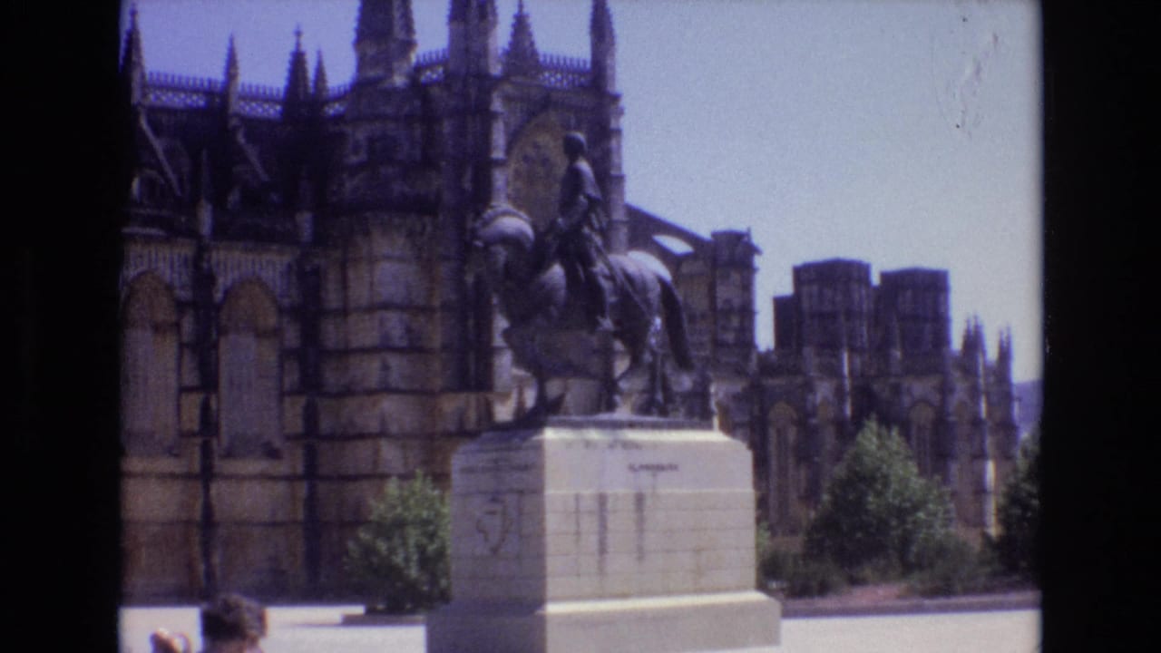 Horseback statue on a pedestal before Gothic stone architecture and a bright plaza.