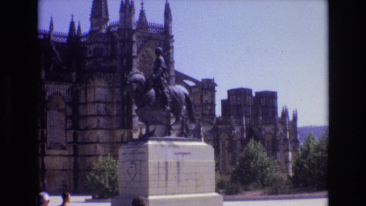 1972 Portugal travel-film frame showing an equestrian statue before a grand stone cathedral facade with towers and arched details.