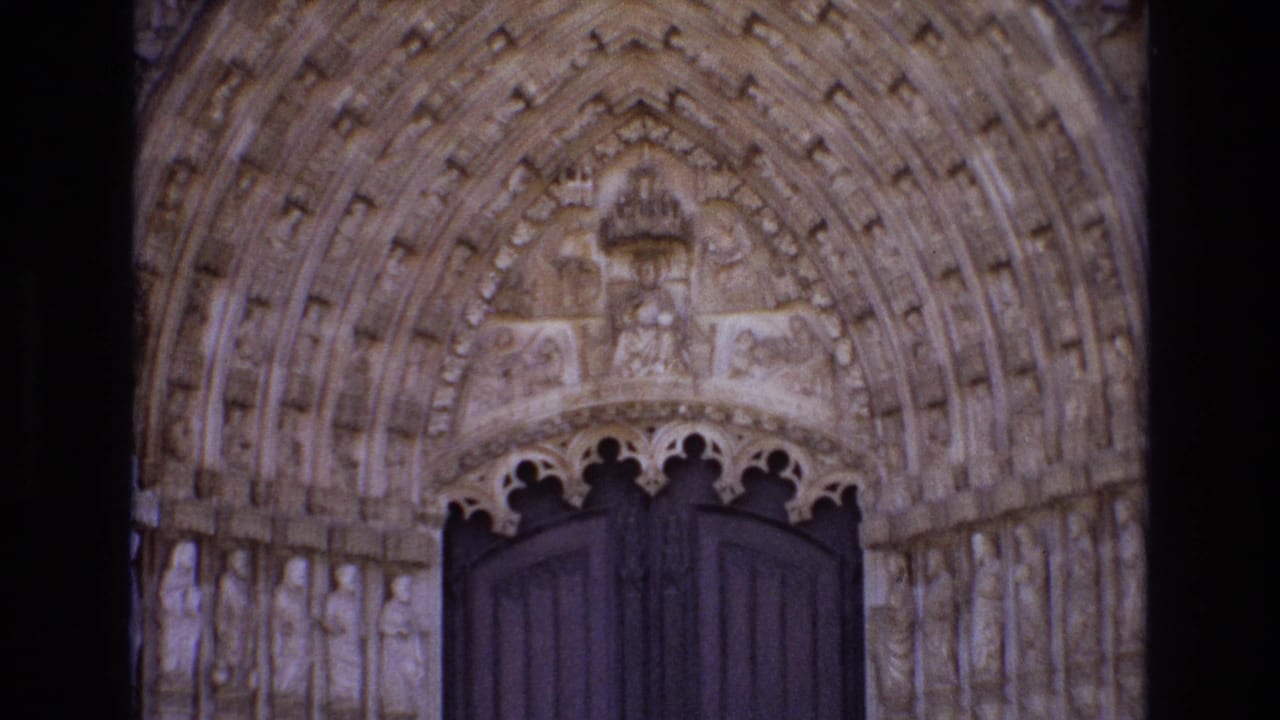 1972 Portugal 8mm frame showing an ornate historic church portal with carved stone figures, layered pointed arches, and dark wooden doors.