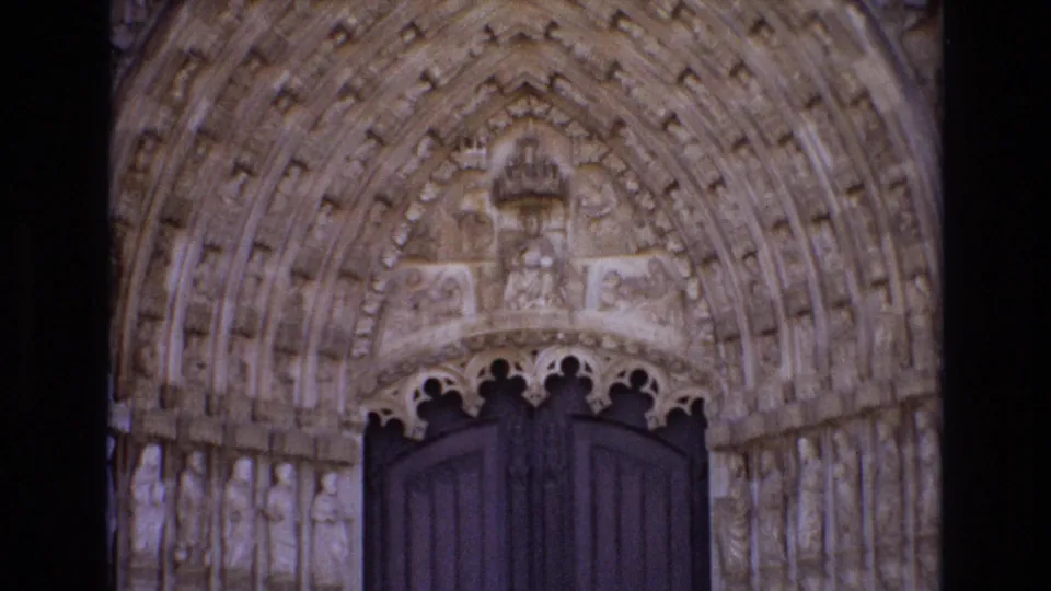 1972 Portugal 8mm frame showing an ornate historic church portal with carved stone figures, layered pointed arches, and dark wooden doors.
