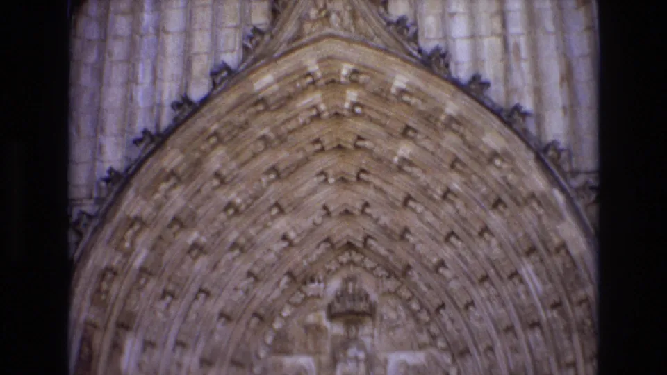 1972 Portugal 8mm frame showing a close upward view of a pointed church arch with repeated carved stone details and weathered vertical masonry.