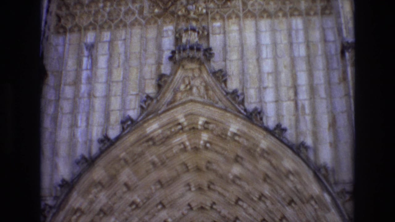 1972 Portugal 8mm frame showing a close visitor-shot view of a Gothic-style pointed arch, pale stone columns, and carved architectural ornament.