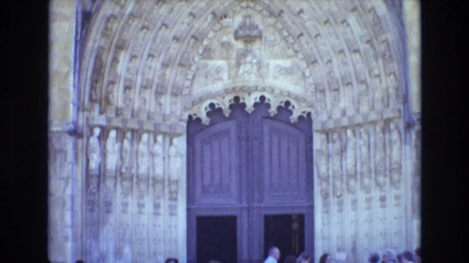 1972 Portugal 8mm frame showing a tall wooden church or cathedral door set below a carved pointed arch, with small visitors visible near the entrance.