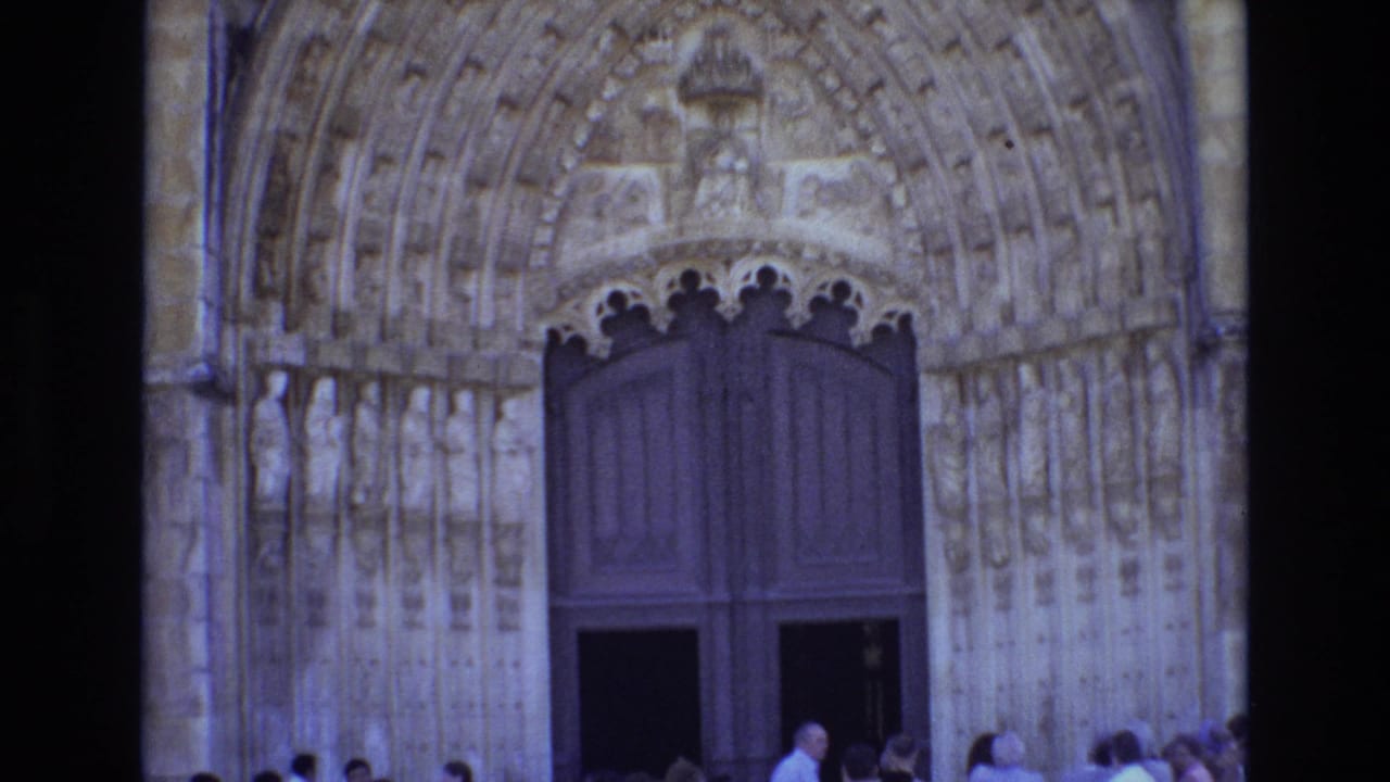 Gothic cathedral doorway with carved stonework and a small crowd gathered near the entrance.