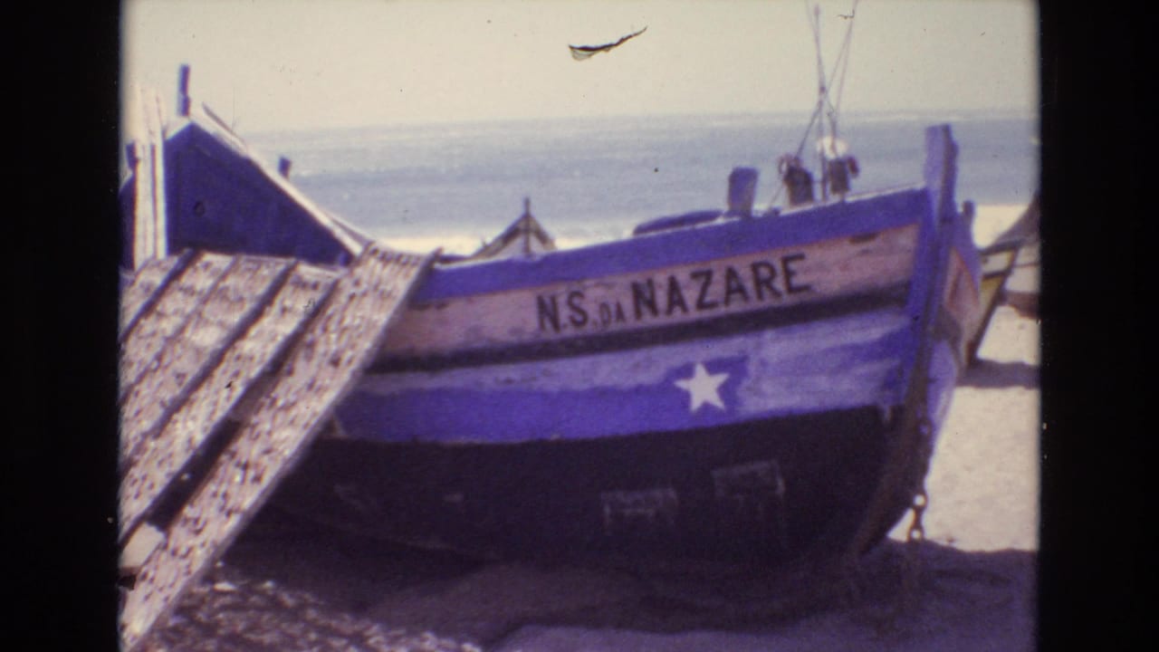 Beached boat labeled NS DA NAZARE beside wooden planks and the sea.