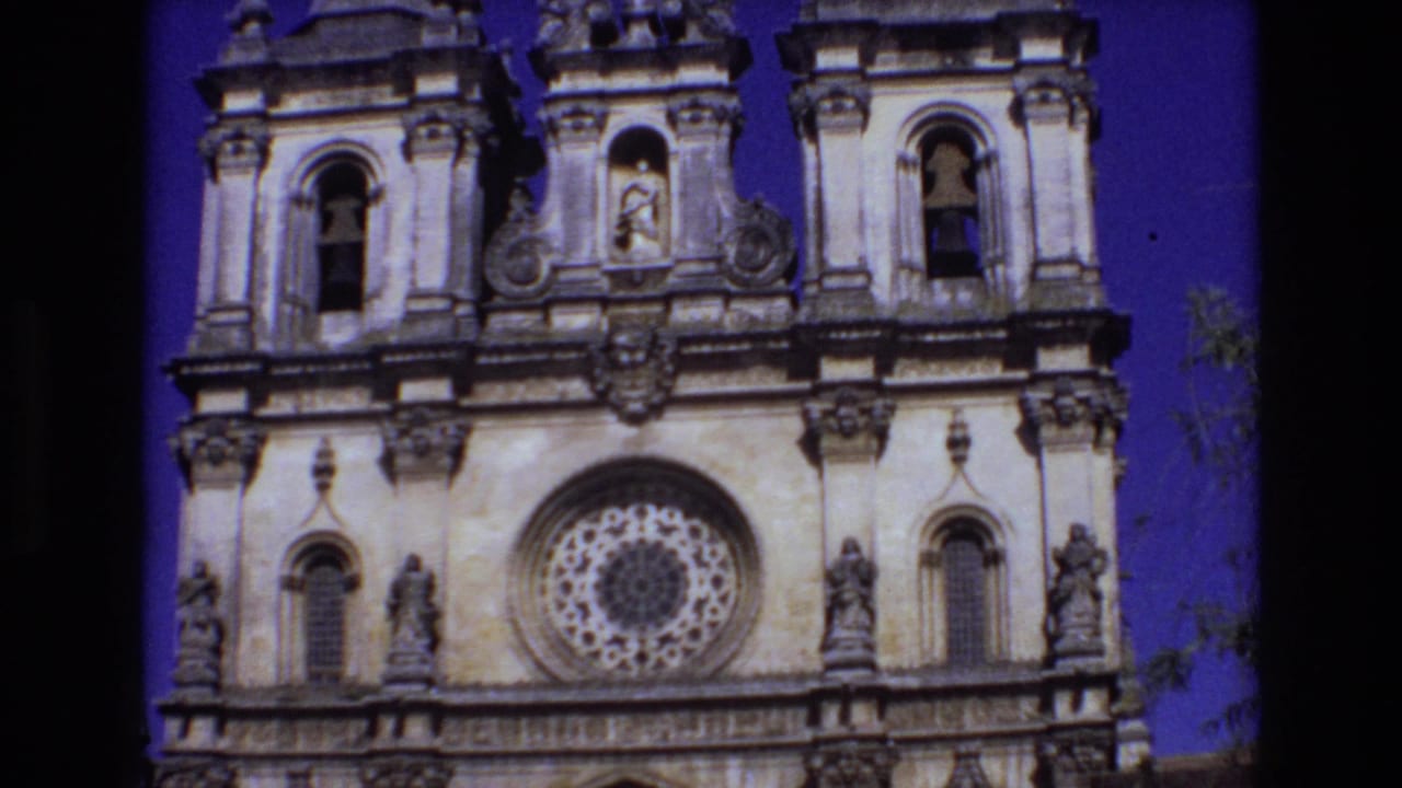 Ornate church facade with bell towers, central rose window, statues, and sky.
