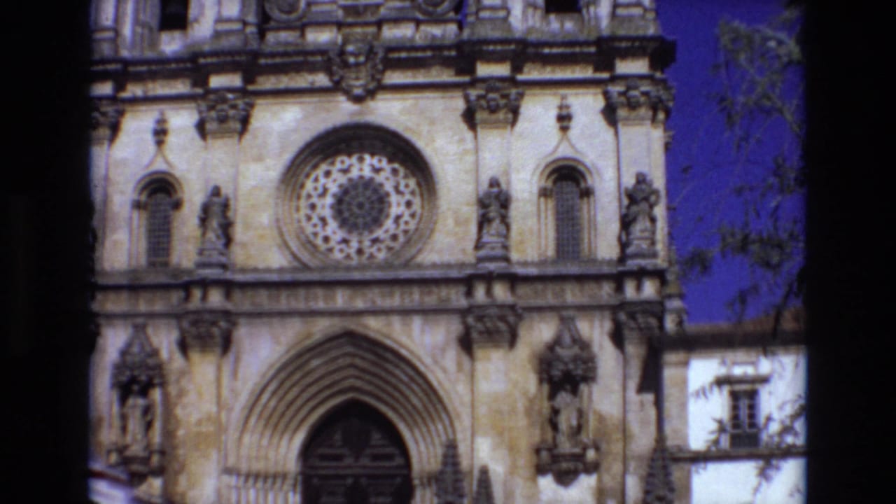 Ornate stone church facade with a rose window and arched entrance framed by dark film edges.
