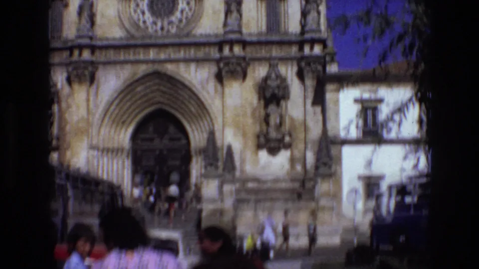 1972 Portugal 8mm frame showing the lower portion of an ornate church facade as visitors walk toward the arched entrance.