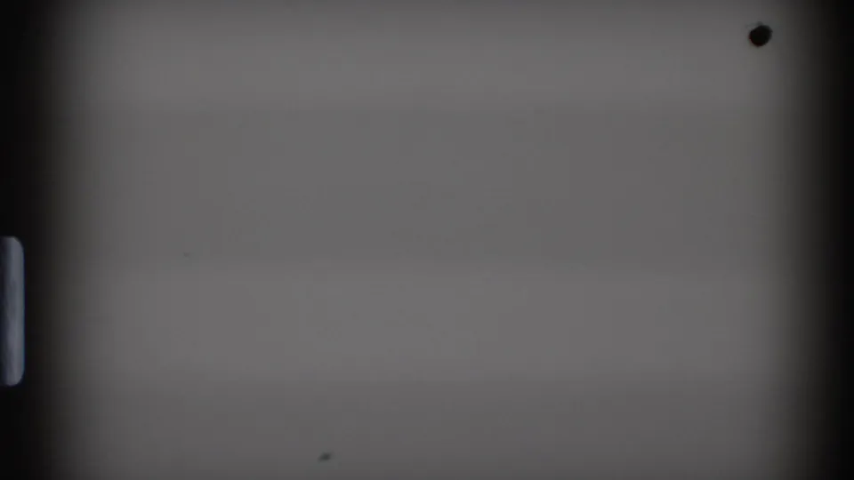 A second mostly blank 8mm frame from the 1972 home movie, with visible gate edges, sprocket area, and minor specks on the film surface.