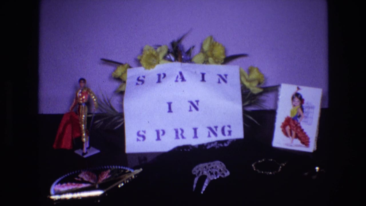 Still life display with "SPAIN IN SPRING" sign, yellow flowers, bullfighter figurine, dancer card, and tabletop ornaments.