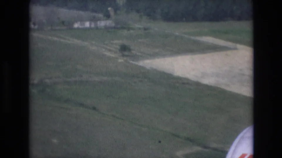 Passenger-window landing view over fields and airport strips in Spain, with partial Iberia aircraft lettering visible at the lower right edge of the frame.