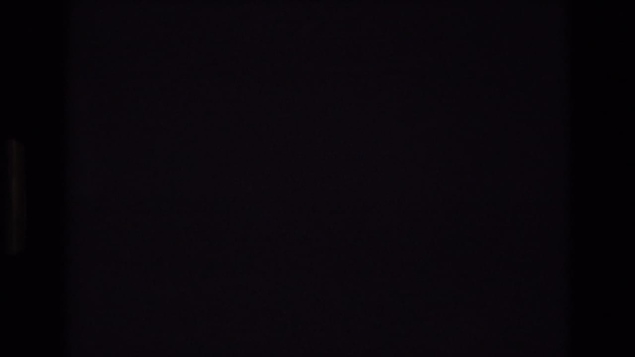 1972 Spain 8mm frame with a mostly dark foreground edge and a partial view of cars moving along a tree-lined urban street.