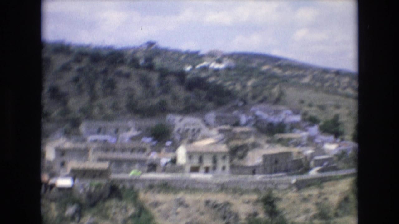 Hillside town buildings seen beyond a road from an elevated viewpoint.