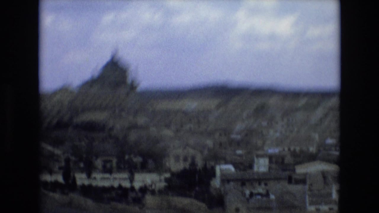 1972 Spain 8mm frame showing a soft, distant overlook of a historic city, with a domed landmark rising above clustered buildings and low hills beyond.