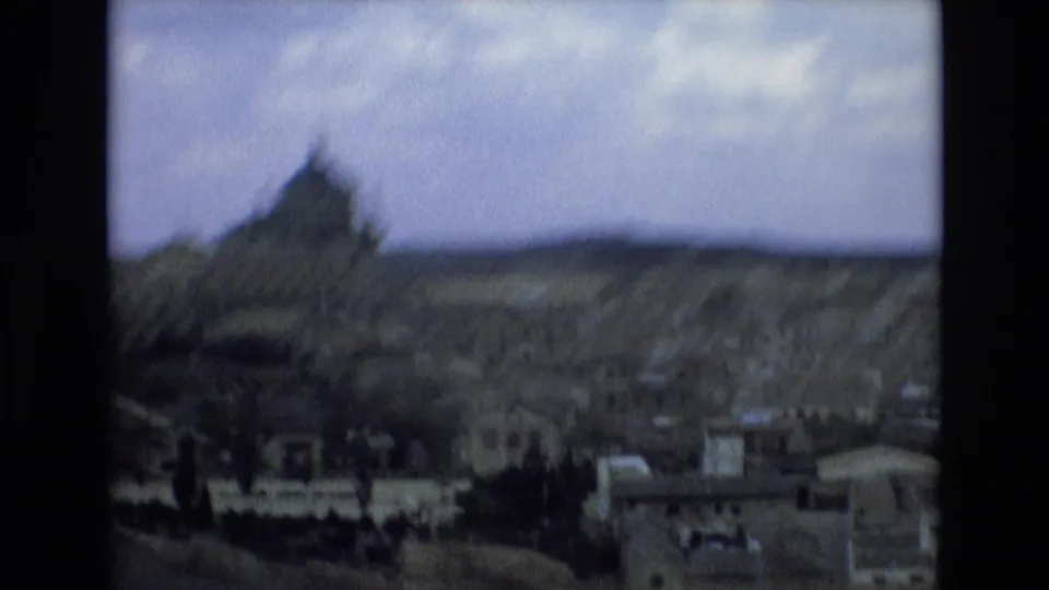 1972 Spain 8mm frame showing a soft, distant overlook of a historic city, with a domed landmark rising above clustered buildings and low hills beyond.