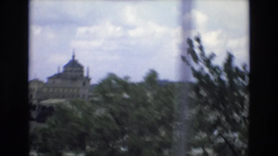 1972 Spain 8mm frame with a large domed historic building seen beyond trees, softened by motion blur and roadside framing.