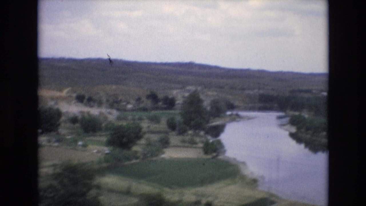 River valley with fields, trees, hills, and power lines.
