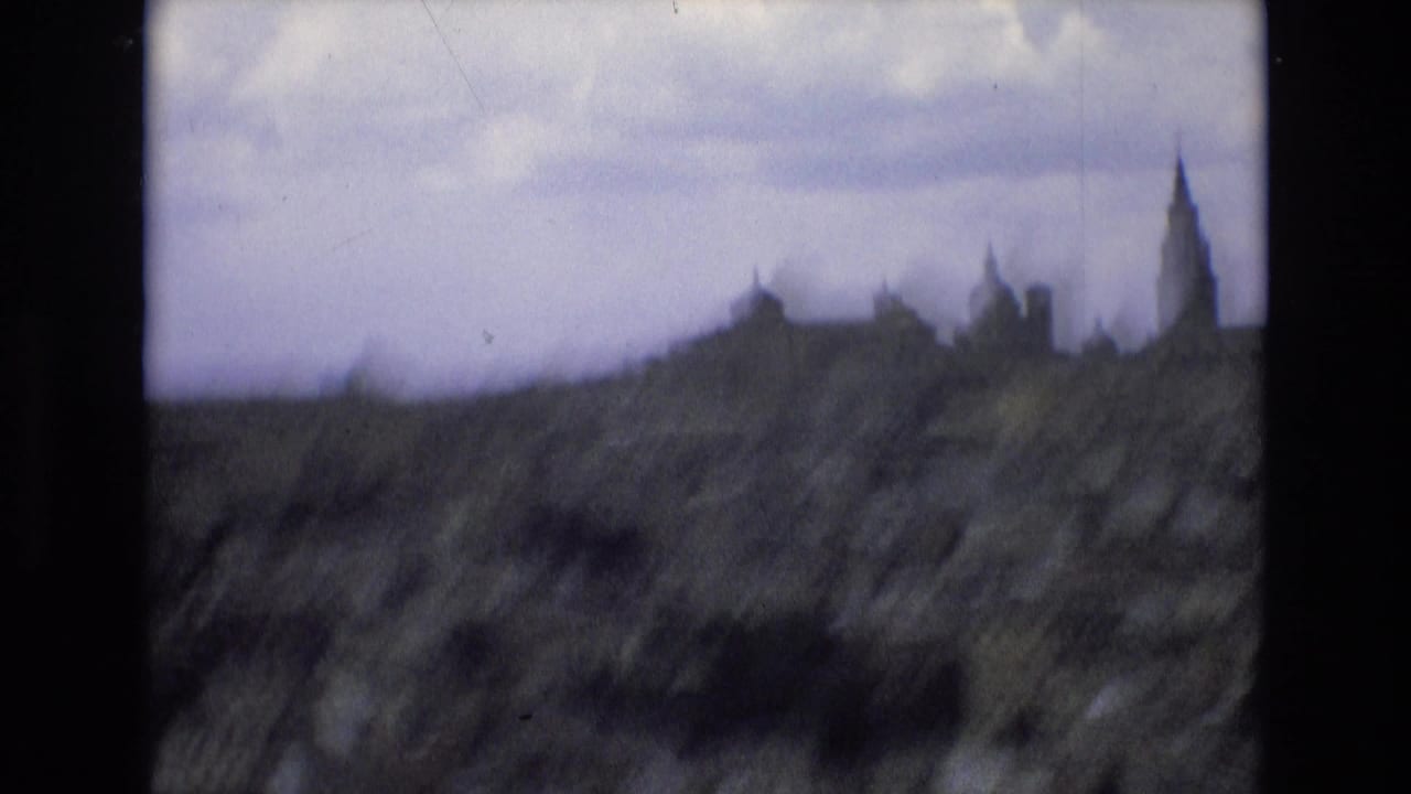 Blurred rocky foreground with a distant skyline and tall spire beyond it.