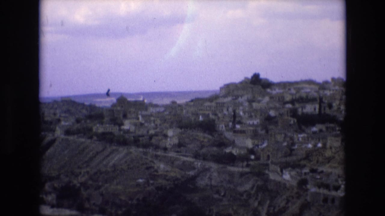1972 8mm Spain travel footage showing a distant hillside town with tightly packed buildings, muted sky, and visible film-frame edges.