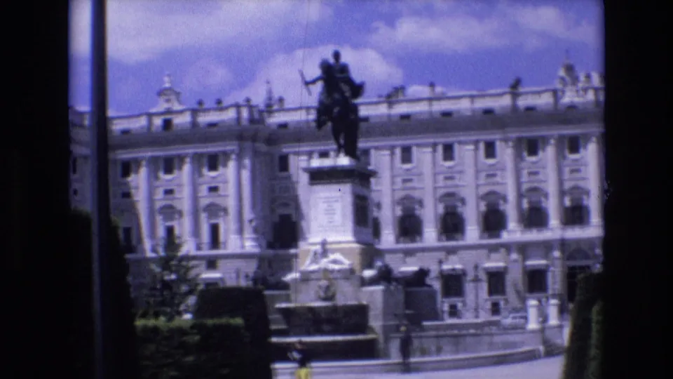 A Spain 1972 archival frame shows an equestrian statue in front of a large formal building, with a plaza, balustrade, and garden edge visible in bright daylight.
