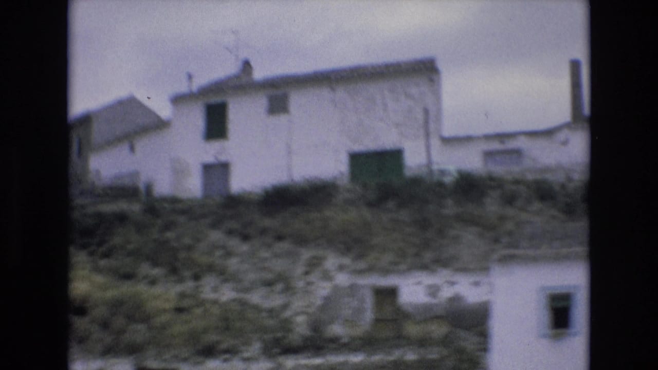 White buildings on a rocky hillside with a green door or gate.