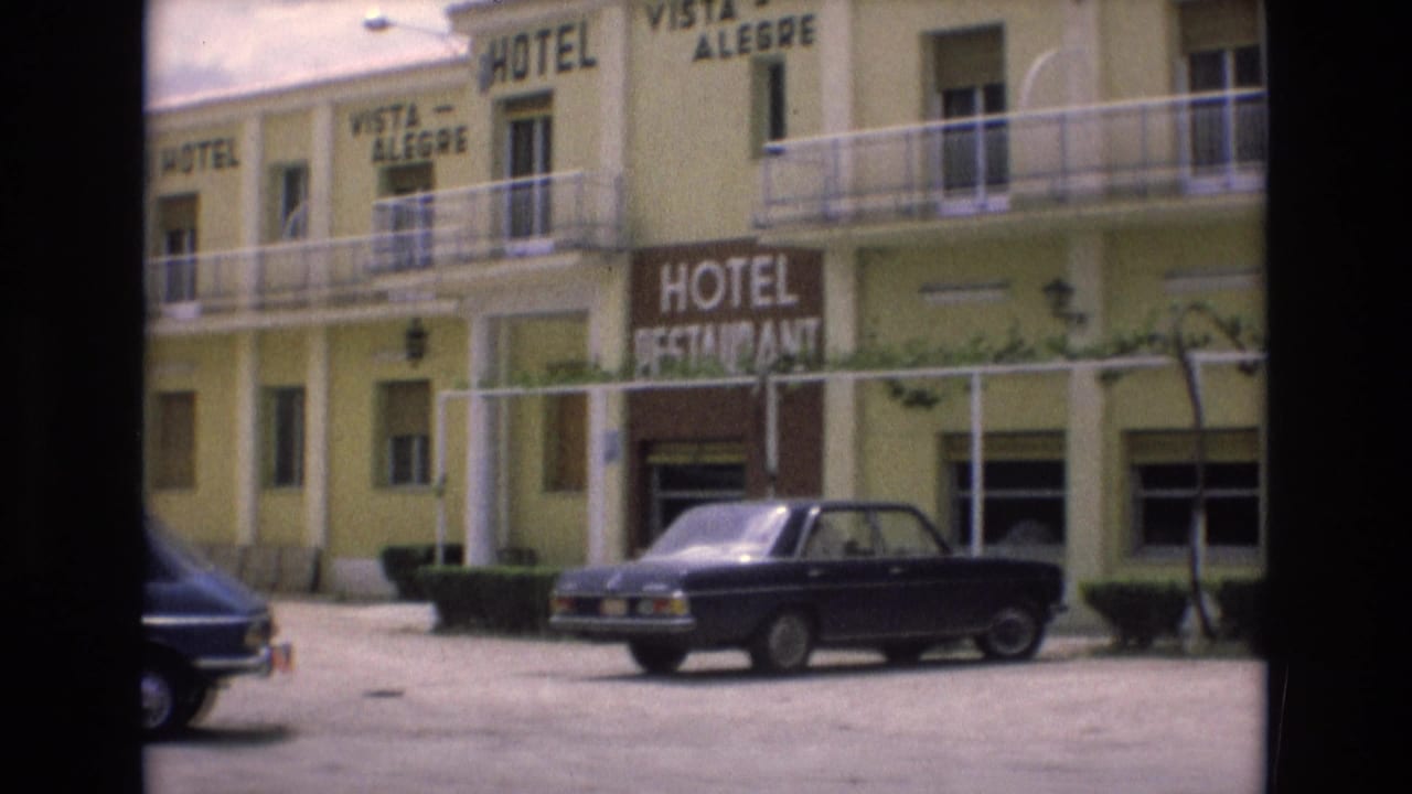 Pale yellow hotel exterior with Vista Alegre signage and parked cars in front.