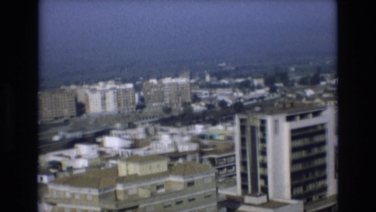 Urban rooftops and apartment buildings with a white high-rise near the foreground.