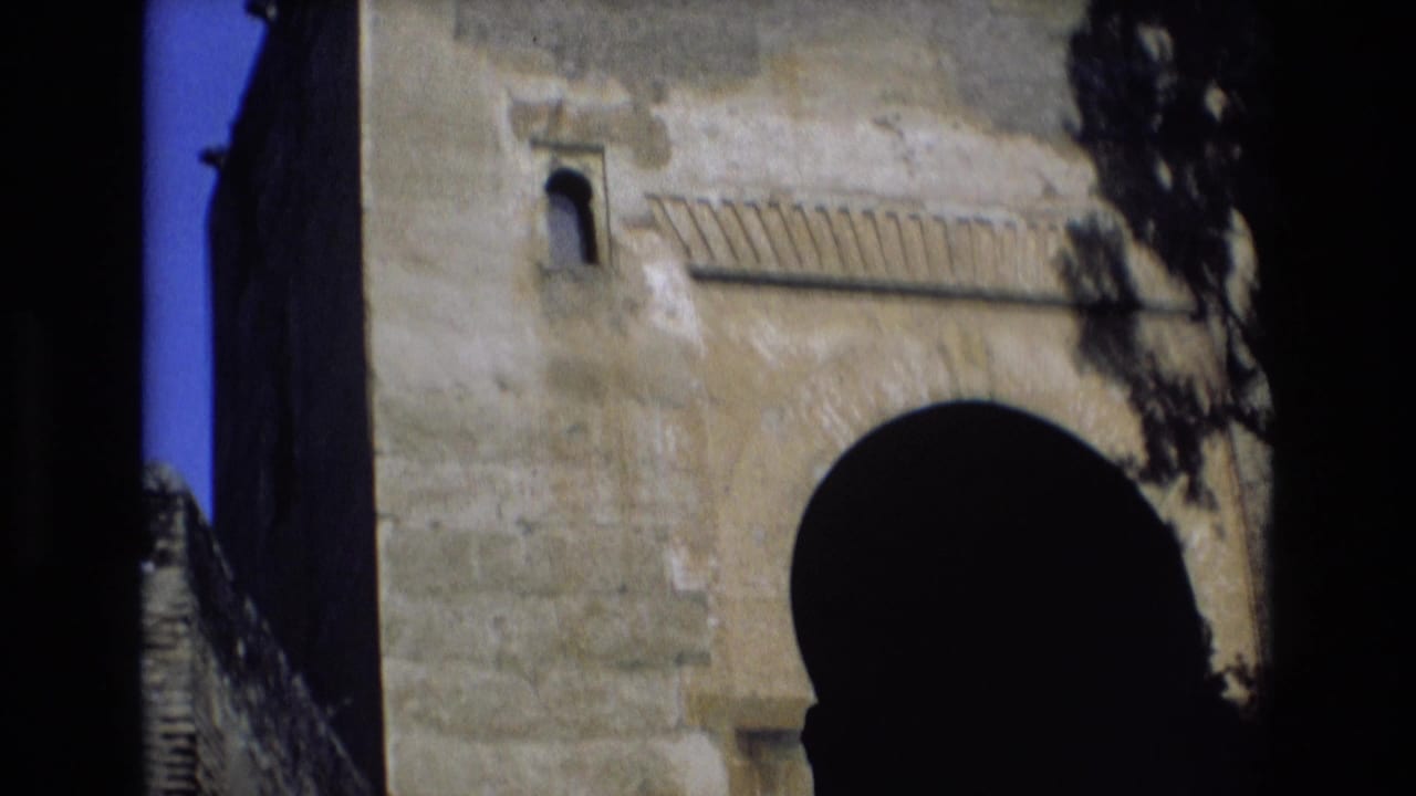 Upper stone wall with small arched opening and large dark arch below.
