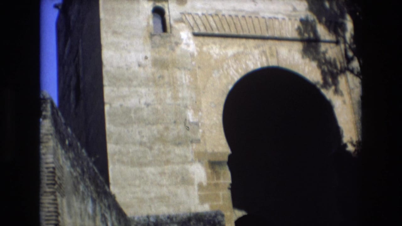 Large dark arch in a stone facade with a narrow window above.