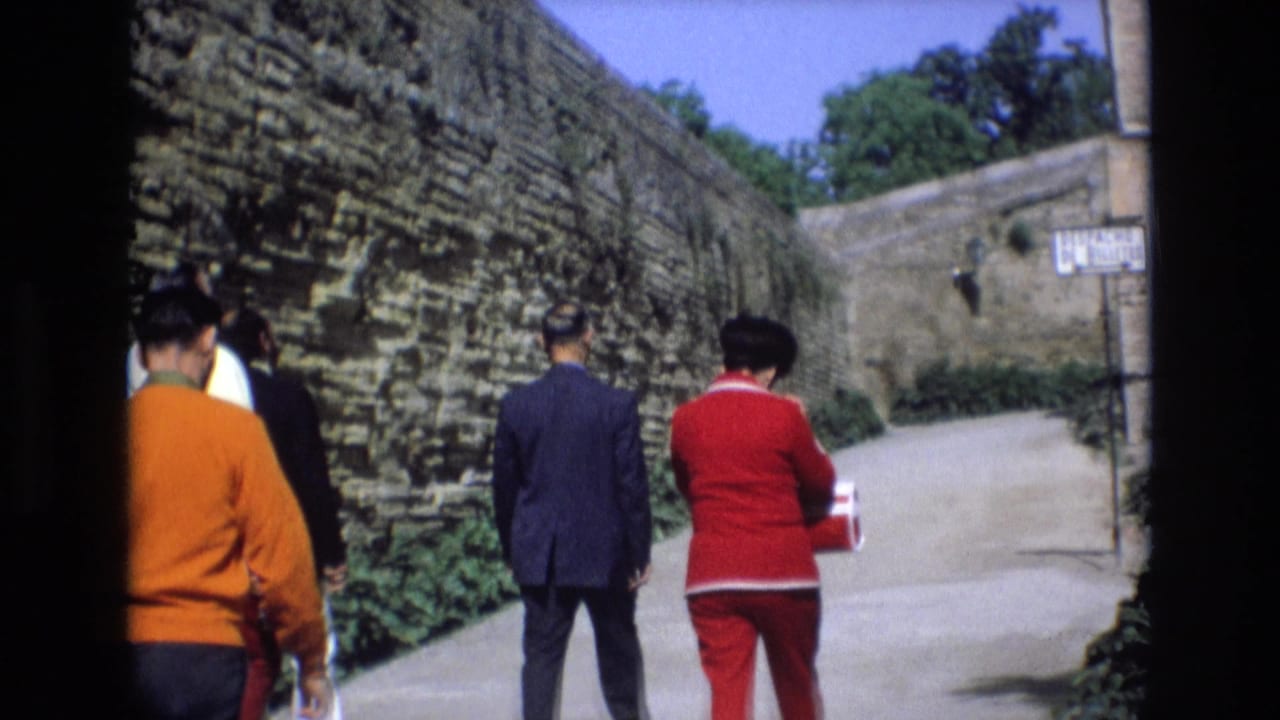 A small group of adults walks toward a bend in a walled path.