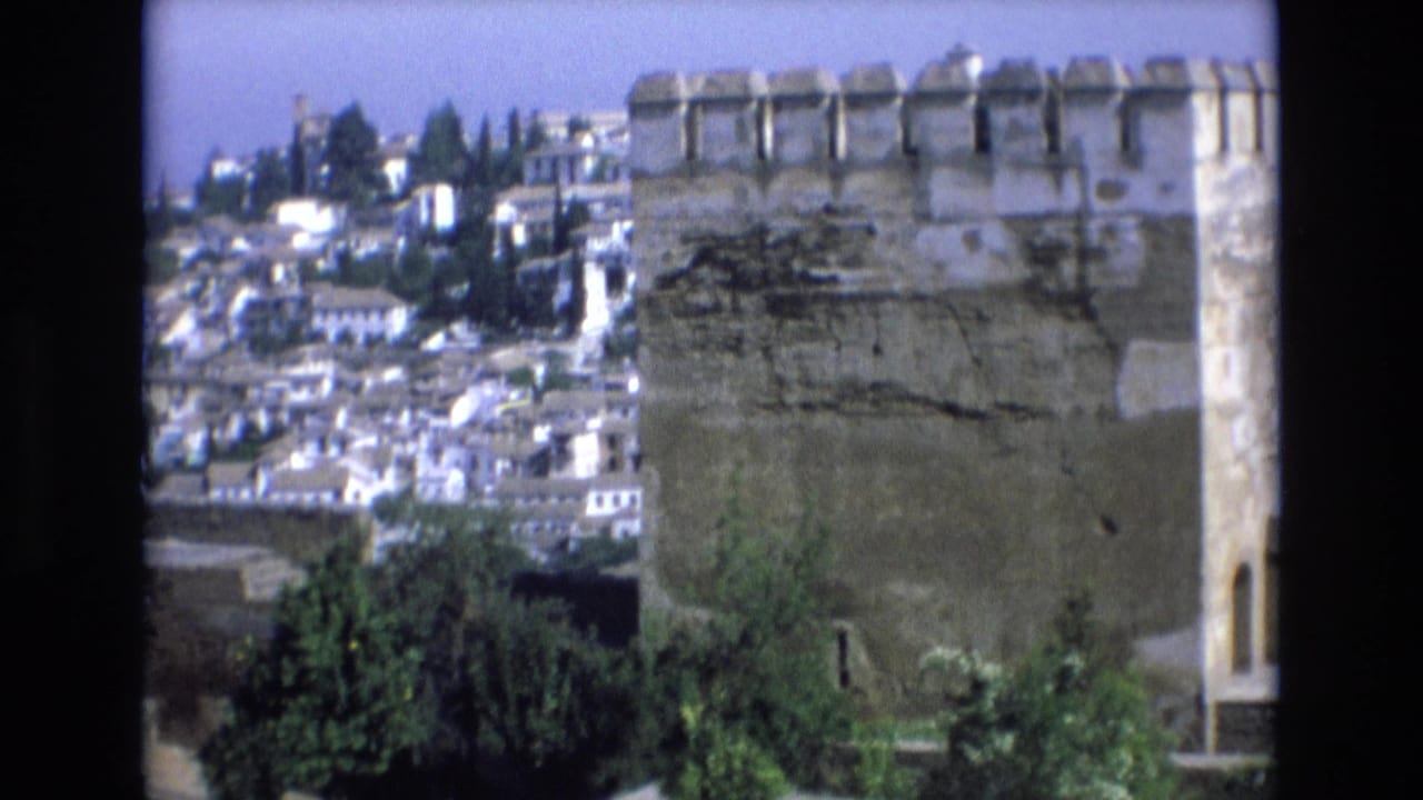 Large stone turret in the foreground with clustered hillside buildings behind it.