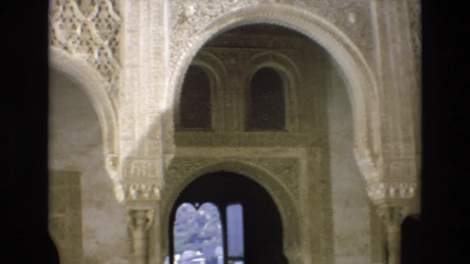 1972 Spain 8mm frame showing a closer tourist view of ornate stucco carving, layered arches, upper windows, and a bright arched opening beyond the interior.