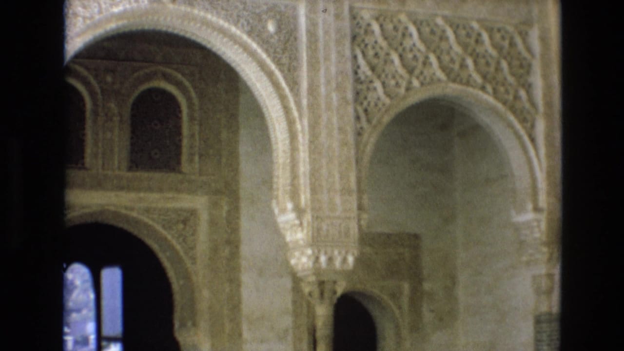 1972 Spain 8mm frame showing ornate Moorish-influenced arches, carved wall surfaces, columns, and shadowed interior openings.