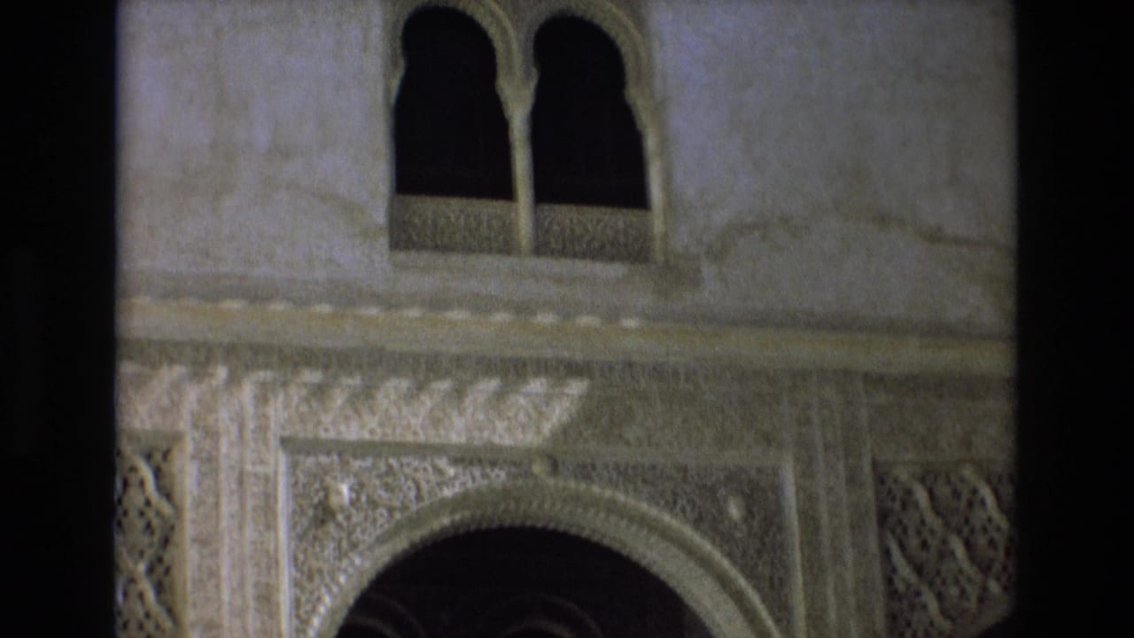 Decorated wall section with paired arched windows above a carved arch.