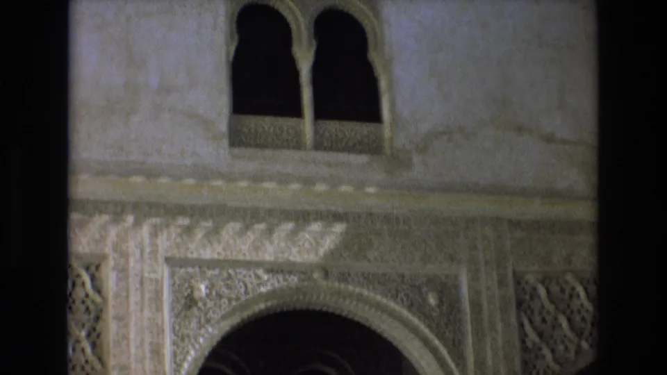 1972 Spain 8mm frame showing paired arched windows, an ornate carved arch, geometric decoration, and pale architectural wall surfaces.