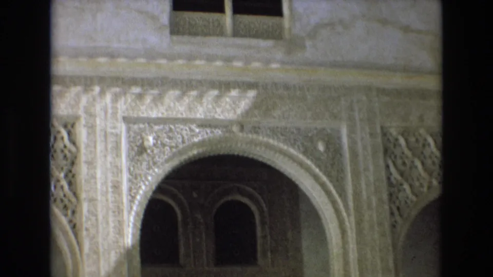 1972 Spain 8mm frame showing a closer visitor-shot view of carved Moorish-influenced archwork, dark arched windows, and patterned wall ornament.