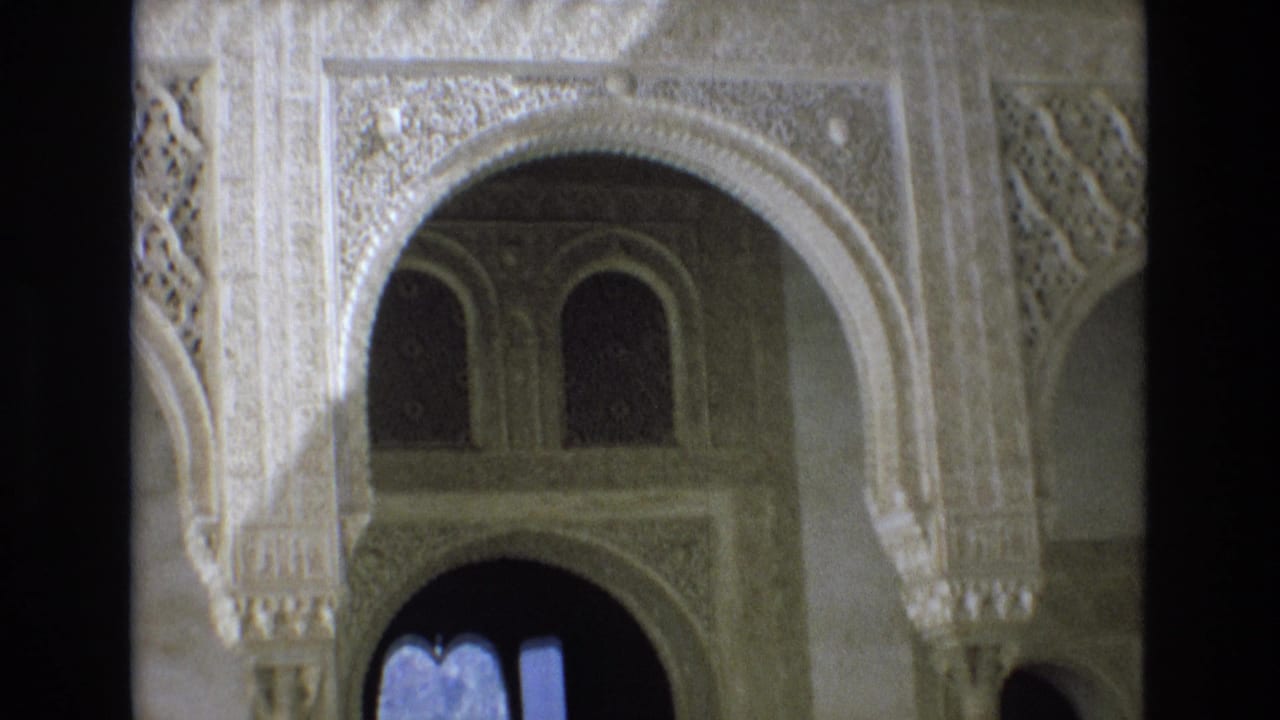 1972 Spain 8mm frame showing Moorish-style carved arches, column details, and shadowed arched openings inside a historic palace setting.