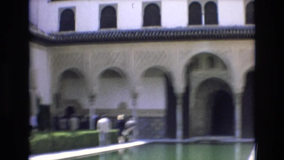 The closing frame shows a slightly softer 8mm view of visitors near the water, with Moorish-style arches, tiled walls, hedges, and a shaded entry in the background.