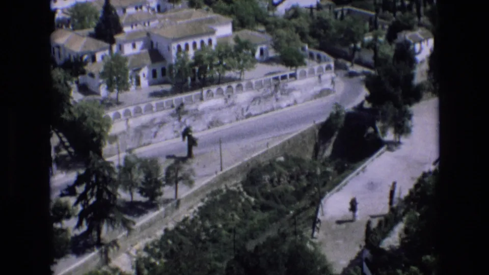 The final 1972 Spain frame shifts to an elevated traveler-shot view of a winding road, white buildings, terraced walls, trees, and landscaped greenery.