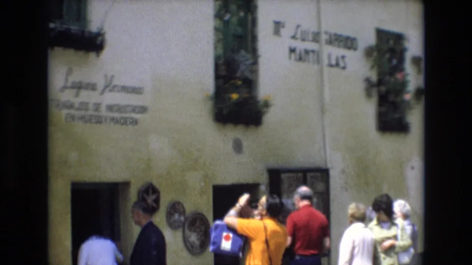 Tourists gather outside a Spanish craft-shop facade marked with lettering for Laguna Hermanos and incrustation work in bone and wood.