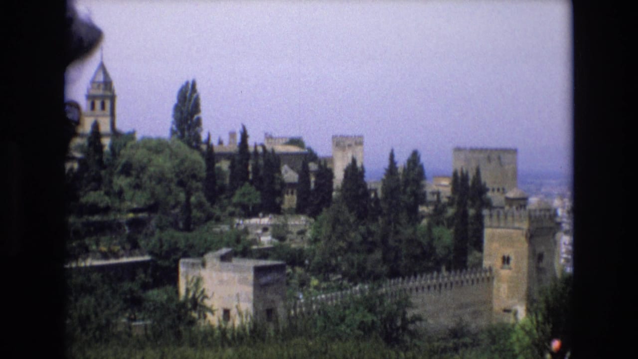 Similar distant view of castle towers and walls surrounded by trees and gardens.