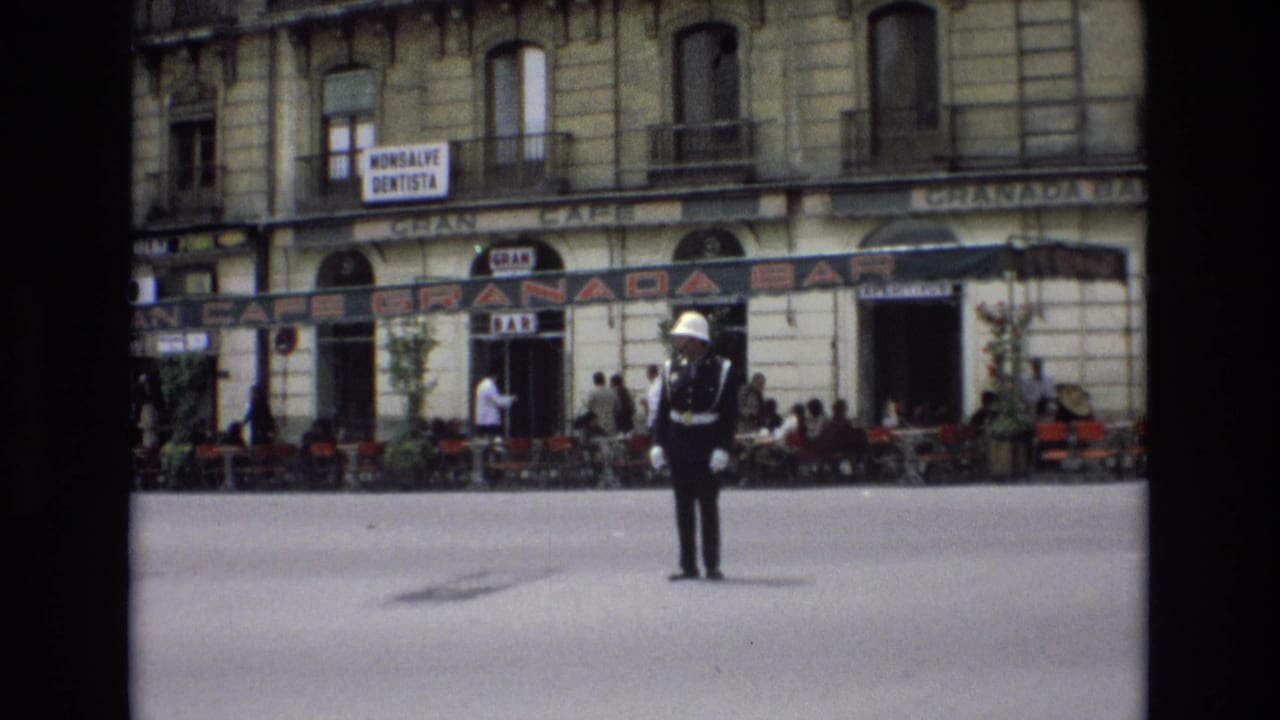 1972 Spain street scene with a white-gloved traffic officer standing at an intersection before Granada Bar signage, pedestrians, and outdoor seating.