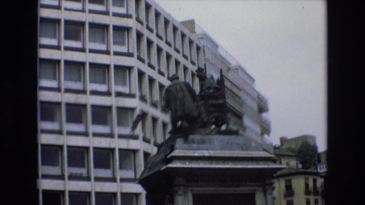Monument and pedestal framed in front of a tall grid-window building.