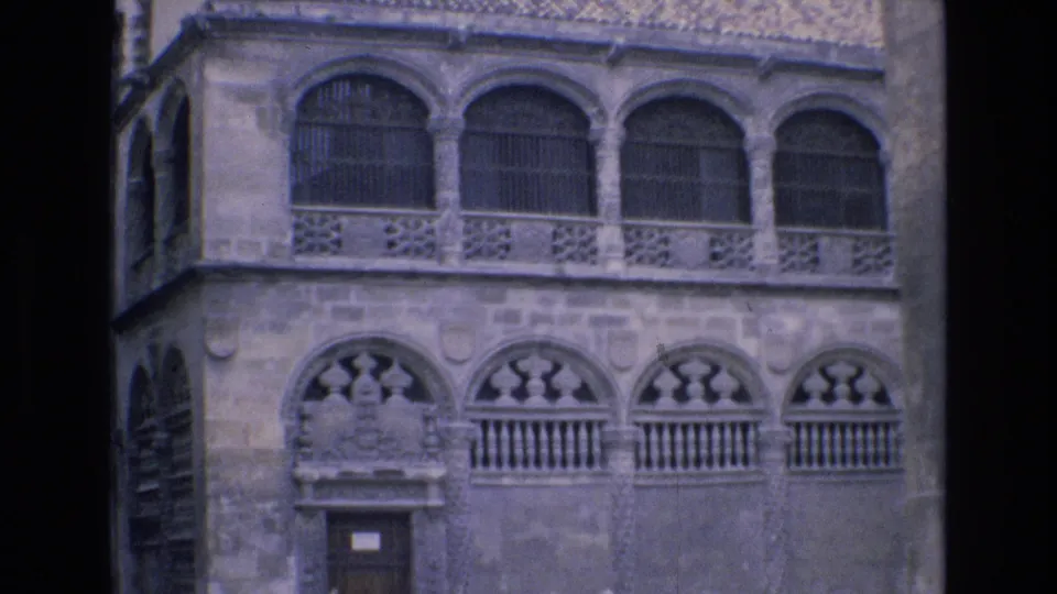 The lower portion of the historic stone building shows carved arch details, balustrades, a doorway, and the left edge of the facade in the supplied Spain 1972 footage.