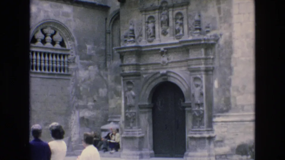 1972 Spain travel footage frame with several visitors facing an ornate historic doorway and carved stone architectural details.