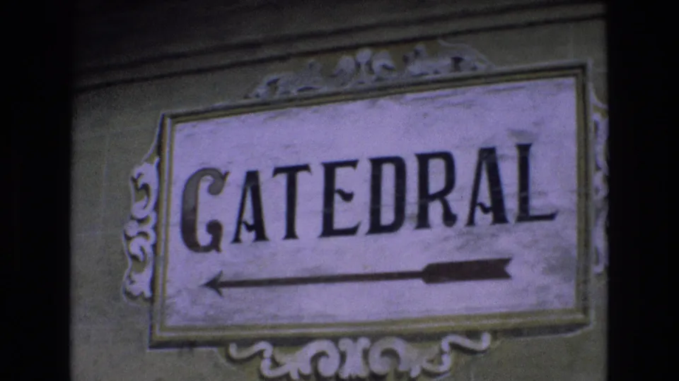 1972 Spain 8mm frame showing a close view of the CATEDRAL wayfinding sign, its painted letters, decorative border, and left-pointing arrow.