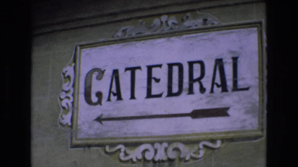 1972 Spain 8mm frame showing the same weathered CATEDRAL wayfinding sign, with bold black letters and a left-pointing arrow.