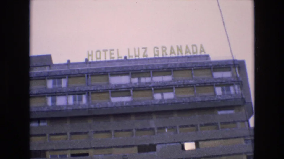 1972 Spain 8mm frame showing the upper facade of a mid-century hotel building with rooftop lettering reading HOTEL LUZ GRANADA.