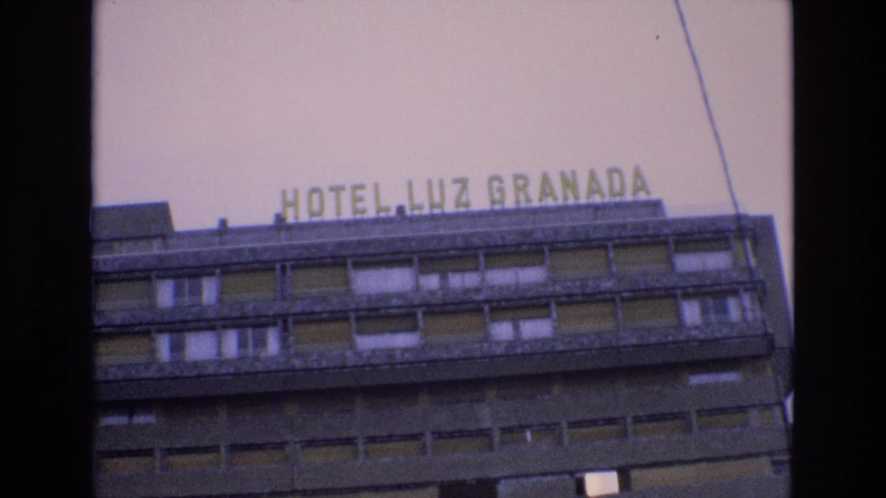 1972 Spain 8mm frame looking up at the HOTEL LUZ GRANADA sign above rows of windows on a concrete hotel exterior.