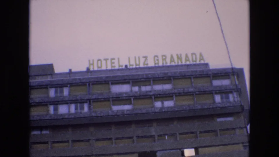 1972 Spain 8mm frame looking up at the HOTEL LUZ GRANADA sign above rows of windows on a concrete hotel exterior.